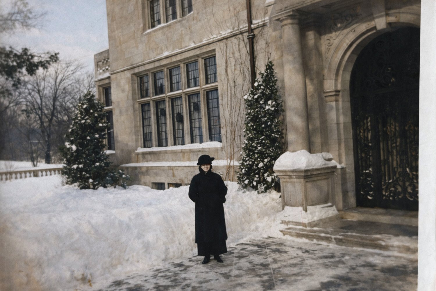 The Charles S. Pillsbury Mansion in Minneapolis under fresh snow, its English Gothic Revival stonework and leaded windows lit for the holidays