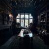 A dark oak-panelled club room inside the Pillsbury Mansion, with a carved stone chimneypiece and a long table set beneath leaded windows.