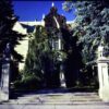 The front steps and stone gateposts of the Charles S. Pillsbury Mansion in Minneapolis photographed in 1980, with mature ivy and evergreens grown up across the English manor facade
