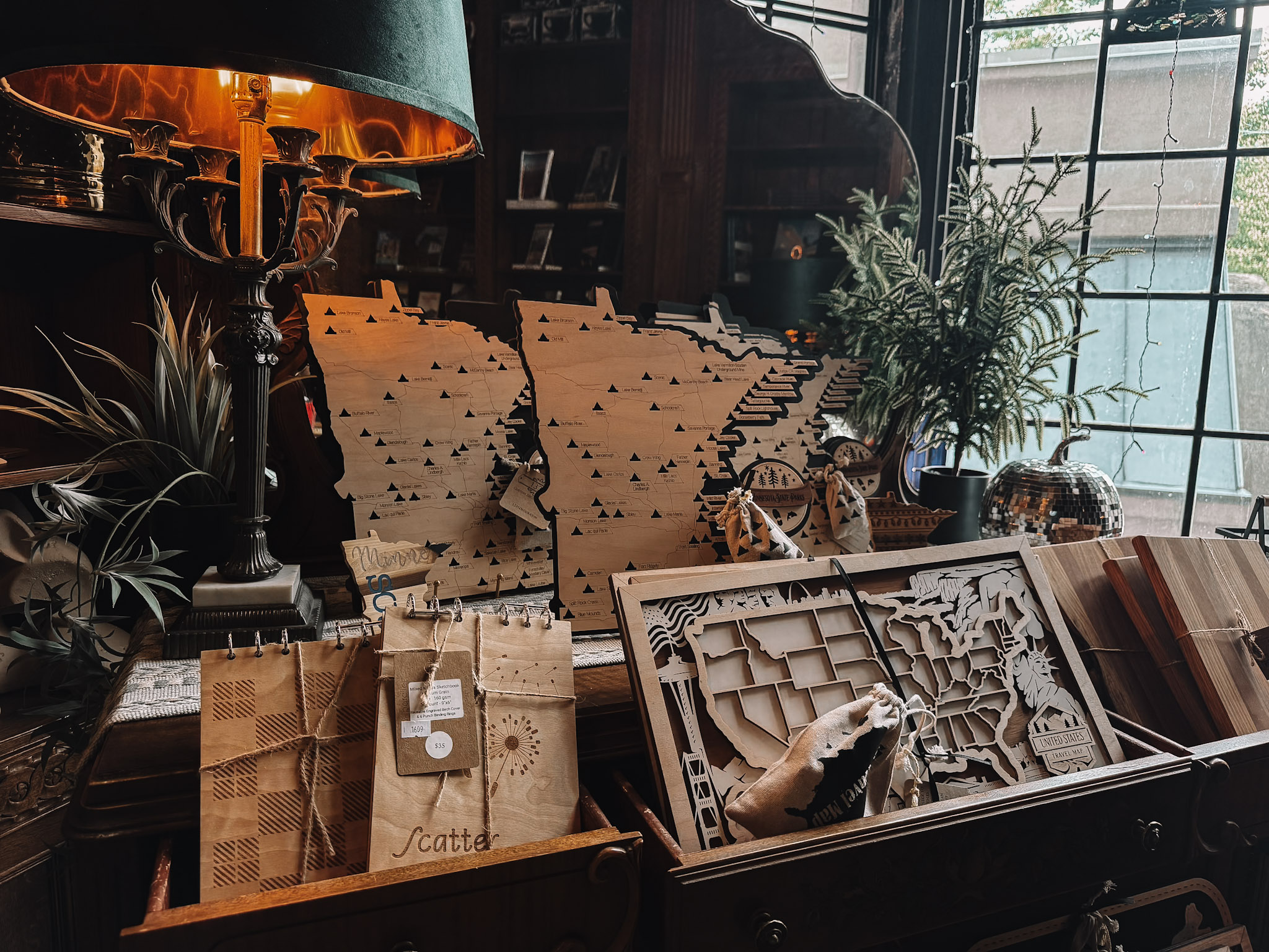 The Pillsbury Club Market, where laser-cut wooden Minnesota maps and Minnesota-made gifts are displayed on an antique sideboard by a leaded window.