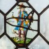 Three painted-glass panels in the Pillsbury Mansion windows labeled America, Europa and Africa, each a single costumed figure inside an octagonal leaded frame